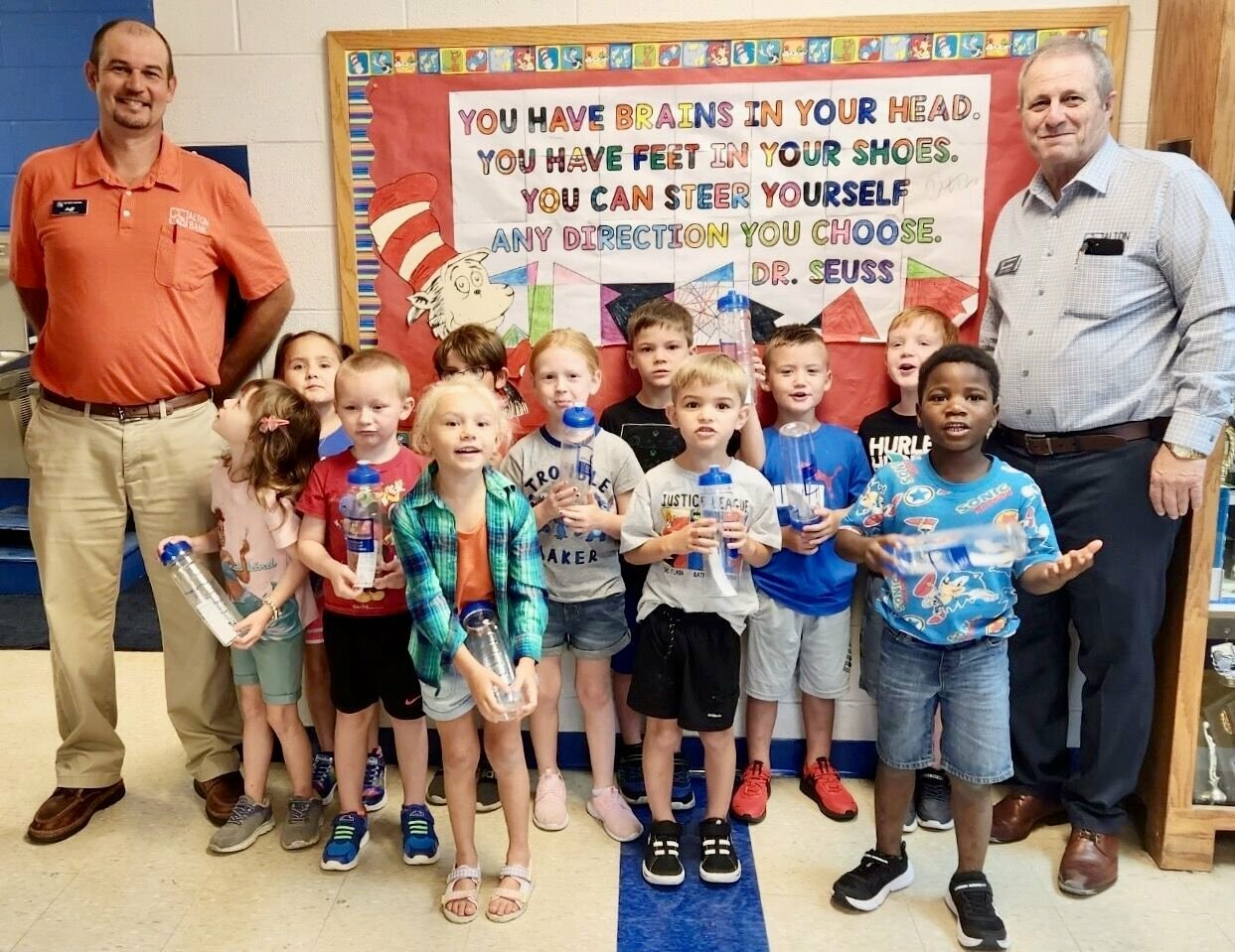 Alton Bank President Randall G. Combs, right, and loan officer Jeffery Roberts recently delivered water bottles to Koshkonong School students and faculty, including these elementary students.